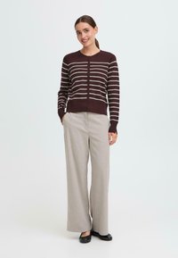 Burgundy striped cardigan with gray lines, button closure, and ribbed cuffs, paired with light gray wide-leg trousers and black flats.