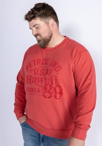 Rode sweatshirt met de tekst "PETROL IND. U.S.A. Hawaii" en een groot nummer "39" in een vervaagde print. Rond de hals en geribbelde boorden.