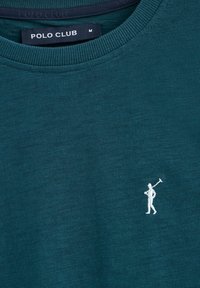 T-shirt in cotone teal con scollatura a coste. Presenta un logo di un golfista ricamato in bianco. Il tessuto ha un aspetto liscio e leggermente testurizzato.