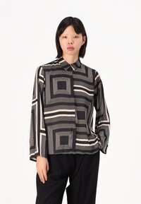 Black and cream long-sleeved shirt with geometric square patterns, featuring a collared neckline and a straight cut. Smooth, lightweight fabric.