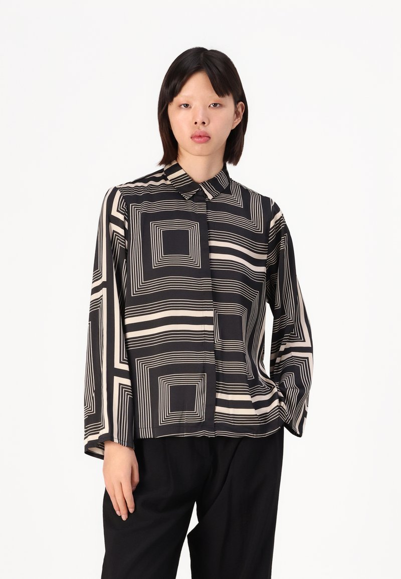 Black and cream long-sleeved shirt with geometric square patterns, featuring a collared neckline and a straight cut. Smooth, lightweight fabric.