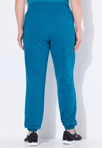 Teal joggers tillverkade av mjukt tyg, med resårmidja och muddar, avslappnad passform och sidofickor.