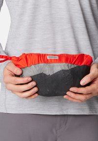 Kompakte Tasche mit rotem Oberteil und schwarzem Netzstoff. Verfügt über einen Reißverschluss und einen Schlaufenhenkel an der Seite für einfaches Tragen oder Befestigen.