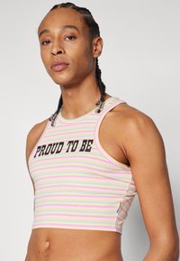 Striped crop top in pastel colors featuring a "PROUD TO BE" print in black. Made from stretchy fabric with a fitted design and sleeveless cut.