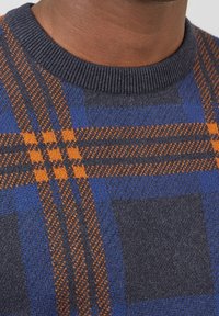 Pull tricoté à carreaux bleus et orange, avec un col rond et un ourlet côtelé. Fabriqué en matière douce avec une texture variée dans le motif.