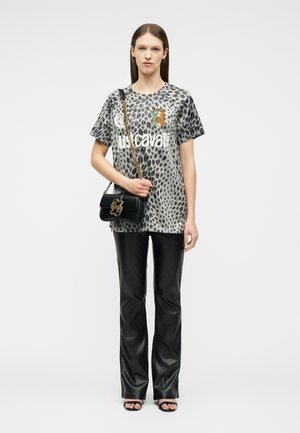 Woman wearing a gray leopard print oversized T-shirt, black leather pants, sandals, and holding a black handbag with a gold chain strap.
