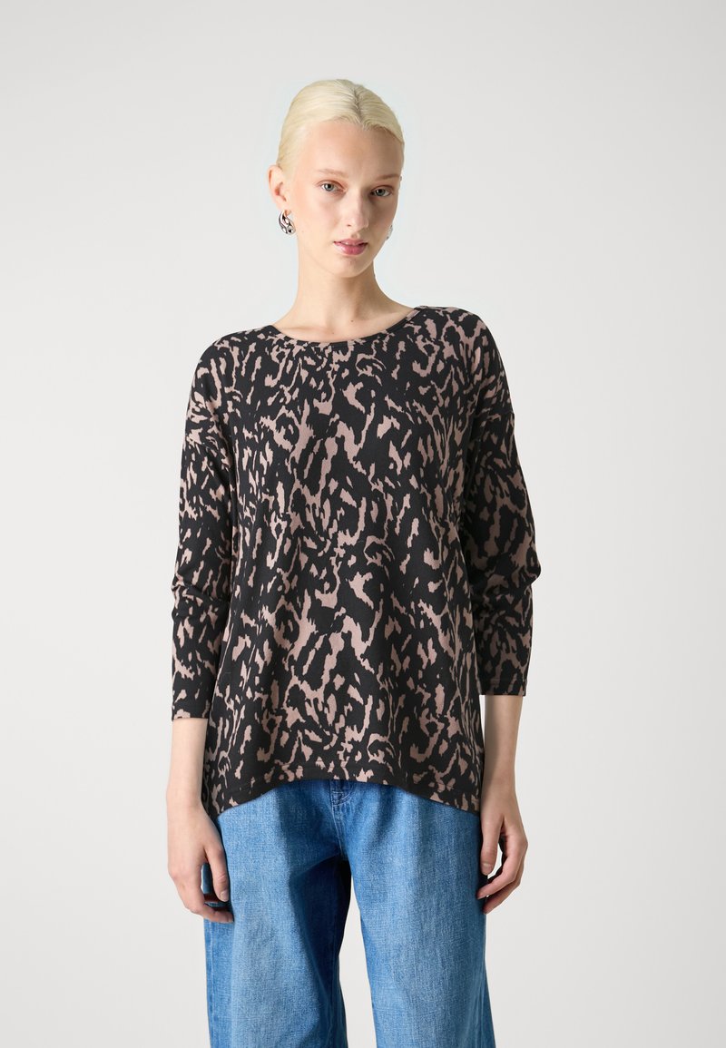 Black and beige leopard print long-sleeve top with a round neckline, relaxed fit, and soft fabric, paired with light blue wide-leg jeans.