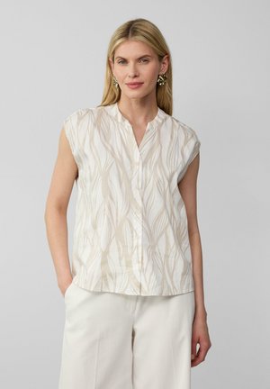 Blouse sans manches en crème avec des motifs de feuilles abstraits beige, présentant un devant à boutons et un col mandarin. Tissu lisse, coupe décontractée.