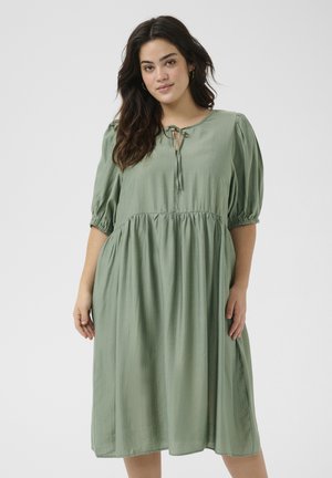 Groene jurk van lichtgewicht stof, met pofmouwen, een ronde halslijn met een strikdetail, en een geraffineerde taille.