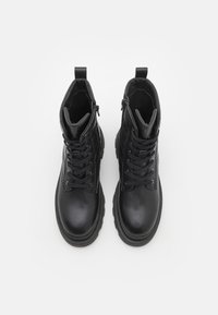 Zwarte leren enkelboots met een zachte textuur, voorzien van een vetersluiting aan de voorkant, een ritssluiting aan de zijkant en stevige rubberen zolen voor extra grip.