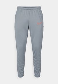 Gray athletic pants with elastic waistband, tapered fit, and contrast orange Nike logo on the left thigh. Smooth, lightweight fabric.