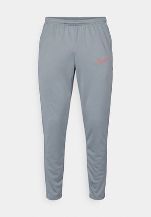 Pantaloni sportivi gri cu talie elastică, croială conică și logo Nike portocaliu în contrast pe coapsa stângă. Material neted și ușor.