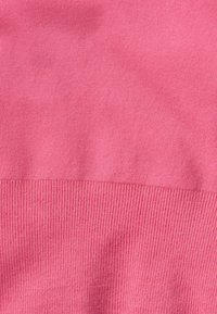 Tessuto di un maglione rosa con una texture liscia, caratterizzato da polsini a coste e di un colore uniforme senza motivi o decorazioni.