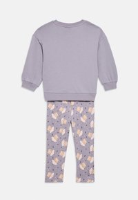 Ljubičasta majica dugih rukava s rebrastim manžetnama u kombinaciji s odgovarajućim helankama s razigranim uzorkom lava i vile.