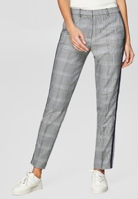 Grijze geruite broek met een smalle pasvorm, voorzien van een marineblauwe zijstreep en een gestructureerde stof. Gestyled met witte sneakers voor contrast.