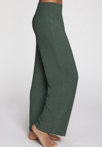 Rebraste široke hlače u tamnozelenoj boji, izrađene od mekanog materijala. Imaju visok struk i opušteni kroj koji se spušta do poda.