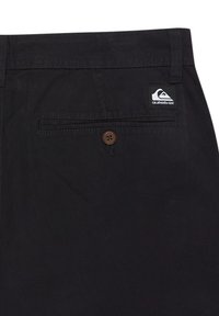 Black shorts with a smooth texture, featuring a rear pocket with a brown button and a small logo tag. Simple design, no patterns.