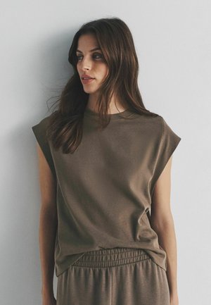 Ärmelloses Oberteil in Olivgrün aus weichem, strukturiertem Stoff mit rundem Ausschnitt und dezent drapiertem Saum, kombiniert mit passenden Hosen.