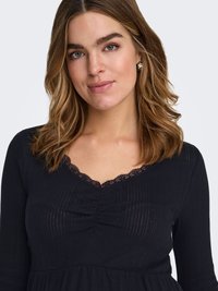 Robe noire à manches longues avec un design côtelé texturé, présentant un col en V orné de dentelle et un détail froncé au niveau de la poitrine.