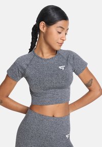 Top deportivo gris recortado con mangas cortas, hecho de un tejido elástico texturizado. Presenta un logo en el lado izquierdo del pecho.