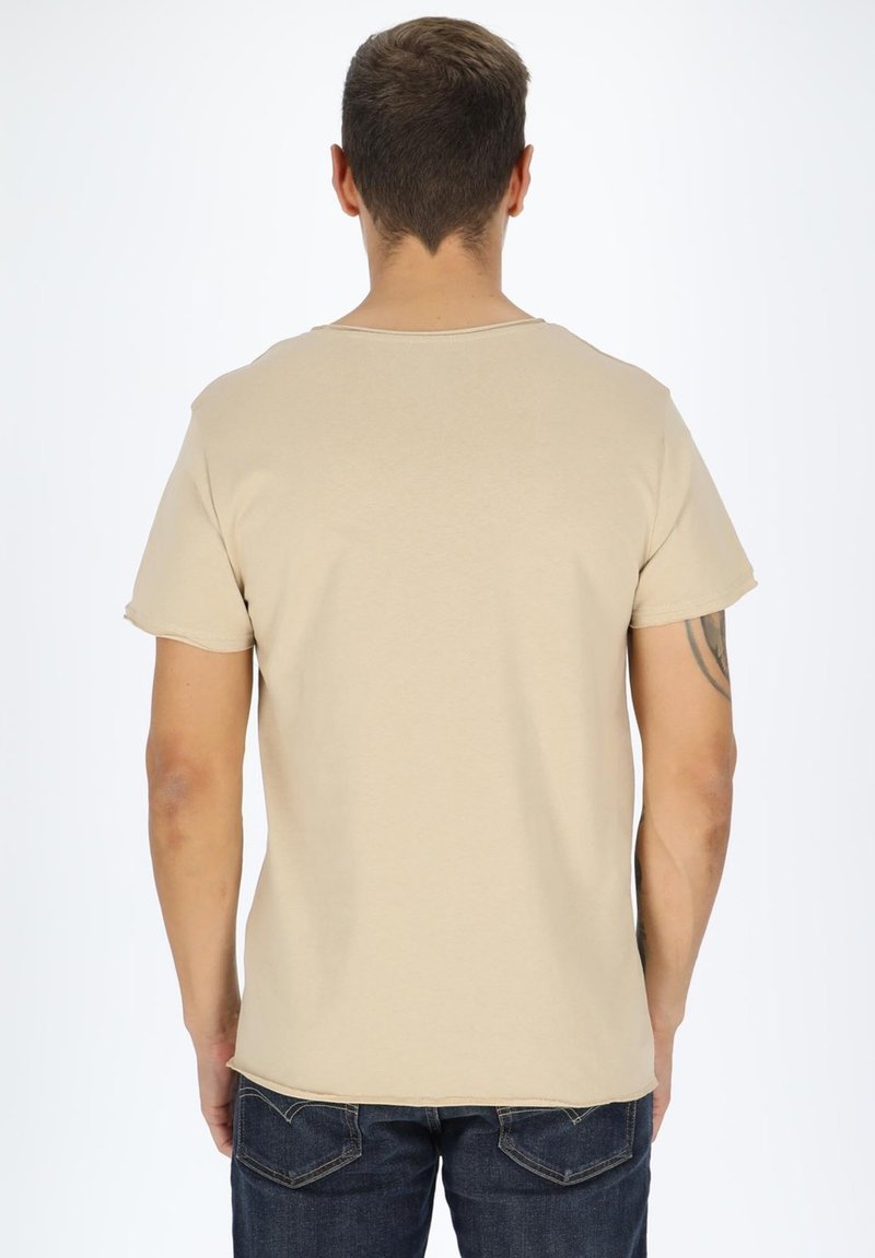Beige cotton t-shirt with short sleeves, round neckline, and a relaxed fit. Worn with dark blue denim jeans. No visible patterns or accents.