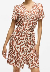 Kortsleeved, knapplåst klänning i ett slätt tyg med ett mönster av zebror i brunt och kräm, med ett knytbälte i midjan.