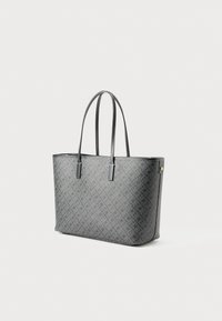 Mørkegrå tote bag med et subtilt geometrisk mønster, sorte håndtak med hvite sting, og detaljer i gullfarge på hvit bakgrunn.