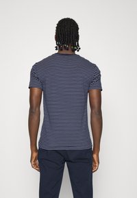 Tmavě modrá košile s krátkým rukávem a bílými vodorovnými pruhy, s kulatým výstřihem a slim fit střihem. Hladká tkanina s jednobarevným zadním dílem.