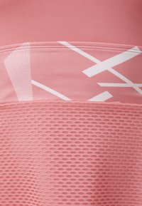 Rózsaszín sportfabia, texturált hálós felülettel és világosabb rózsaszín mintázatokkal. Jellemzője a sima, rugalmas anyag és a kontrasztos geometrikus formák.