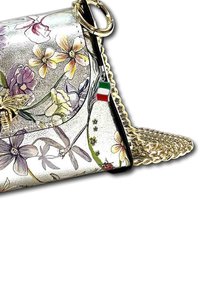 Metalen handtas met bloemenpatroon en gouden kettingband, verfraaid met een bijmotief, zwarte afwerking en een accent van de Italiaanse vlag.