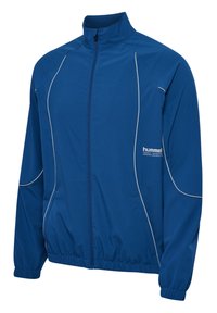 Blå zip-up jacka med hög krage, tillverkad av ett slätt, lätt material. Har vita detaljer och en broderad logotyp på vänster bröst.