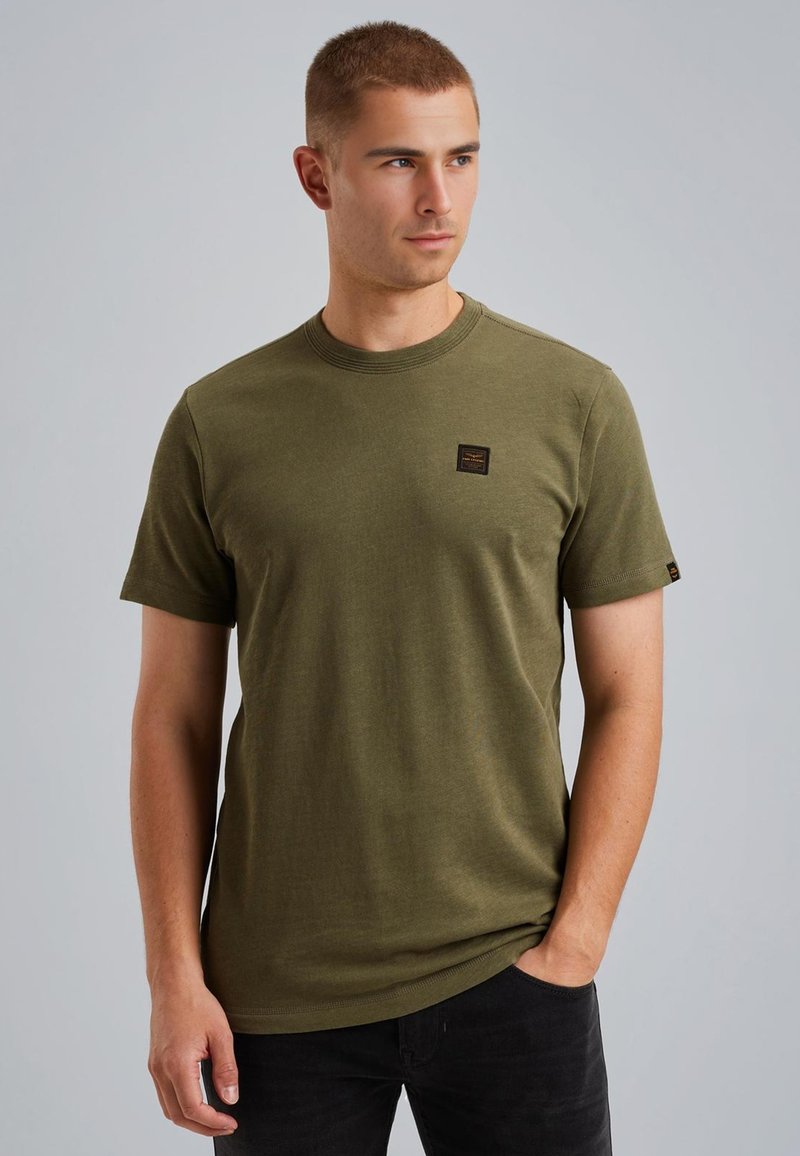 Olijfgroen katoenen t-shirt met korte mouwen, ronde halslijn en een klein bruin label op de borst. Zachte textuur, ontspannen pasvorm.