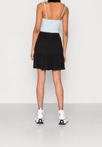 Ljusblå kort topp med spagettiband, matchad med en svart volangkjol och vita ankelstövlar med en svart stjärndetalj.