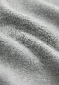 Gray knitted fabric with a soft texture, showing subtle variations in tone and a slightly stretchy appearance.