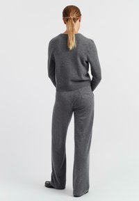 Maglione grigio in maglia e pantaloni a gamba larga coordinati. Texture morbida, aderente in vita con un dettaglio della tasca sul retro dei pantaloni. Design semplice.