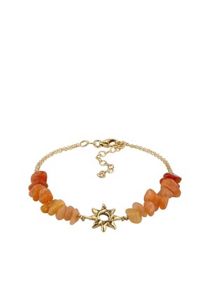 Gold chain bracelet with irregular orange stone beads and a central gold sun-shaped charm with a hollow center.