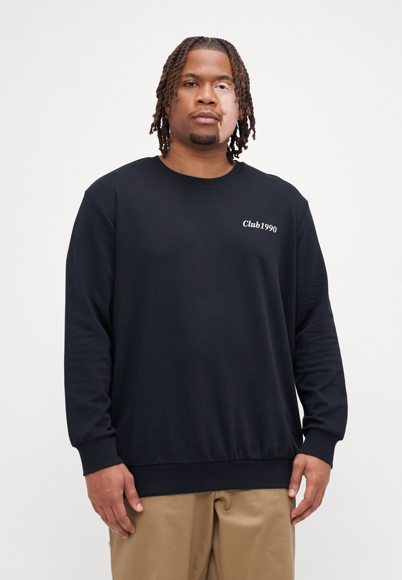 Czarny sweatshirt z okrągłym dekoltem wykonany z miękkiego materiału, z białym haftem "Club1990" po lewej stronie klatki piersiowej, luźny krój i długie rękawy.