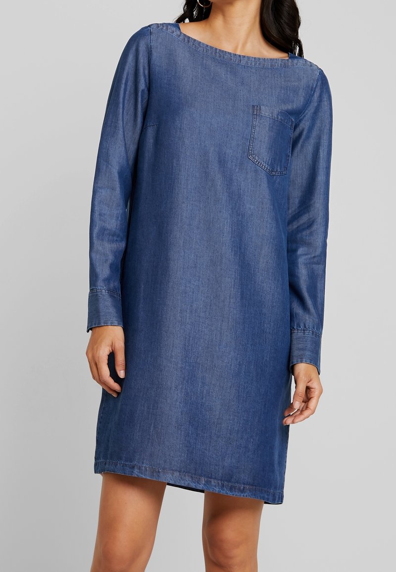 Tummansinisestä denimmekosta, jossa on pitkät hihat, pyöreä pääntie ja rintatasku. Mekko on rento ja suora malli.