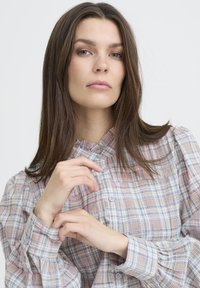 Hemdenbluse aus leichtem, strukturiertem Stoff mit einem mehrfarbigen Karomuster. Verfügt über einen gerafften Kragen und Manschetten mit Knöpfen.