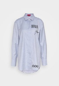 Chemise à manches longues rayée bleu et blanche, en tissu léger, col classique, accent logo sur le devant, doublure légèrement plus longue à l'arrière.