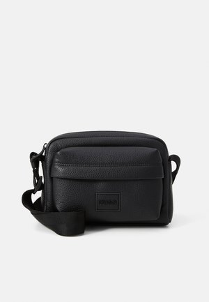 Black leather crossbody bag with a textured finish, zippered main compartment, front flap pocket, and adjustable strap. Features logo on front.