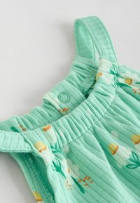 Mintgrøn stofbluse med ribbet tekstur, blomster mønster i gult og hvidt, samlet halsudskæring og justerbar knaplukning.