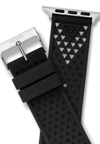 Bracelet de montre en caoutchouc noir avec un motif triangulaire, boucle en métal argenté avec gravure "GUESS", et un design épuré avec des découpes.