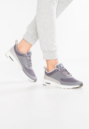 Harmaat Nike-tennarit, joissa on verkkokangasta ja mokkaa, pyöreä kärki, pehmustettu nilkkaosa ja näkyvä ilmayksikkö valkoisessa pohjassa.