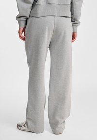 Hellgraue, weite Sweatpants aus weichem Material mit einem elastischen Bund und ohne sichtbare Nähte. Sie bieten einen lockeren Schnitt an den Knöcheln.