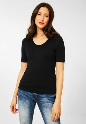 T-shirt nera a maniche corte con collo rotondo. Il tessuto ha una superficie liscia, abbinata a jeans blu sbiaditi per un look casual.