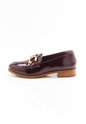 Mocasines de charol burdeos con un bajo tacón apilado y detalle en cadena de tono dorado en la parte delantera. Textura suave, diseño elegante.