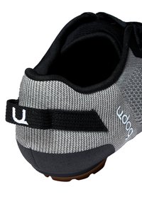 Baskets de sport noires et grises avec une tige en maille, design texturé, languette de talon noire et semelle extérieure en caoutchouc. Présente un logo sur le côté.