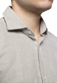 Camisa abotonada gris claro hecha de una tela texturada, con un cuello puntiagudo, costuras visibles y un cierre de un solo botón.