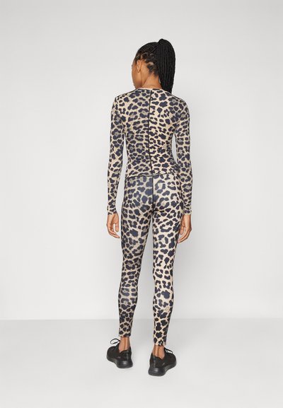 Bodysuit z leopardskim dizajnom s dolgimi rokavi, prilagojena zasnova in zadrga na hrbtu. Obučen z črnimi športnimi copati, brezšivna tekstura.